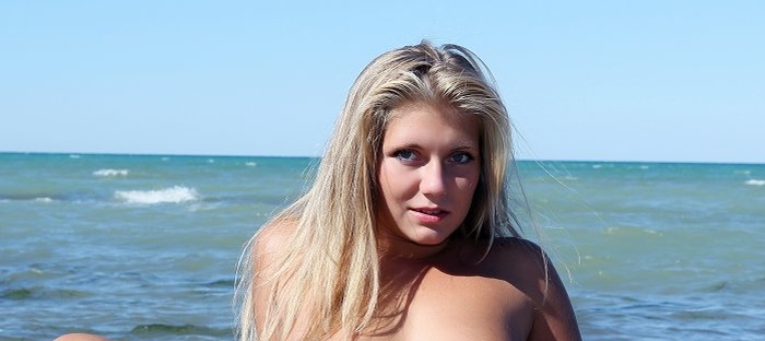 Blondje met grote borsten naakt op het strand