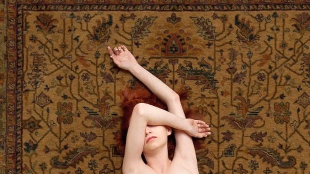Naakte vrouw op een tapijt