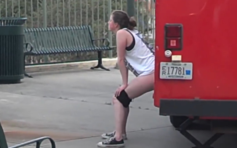 Vrouw plast in het openbaar, naast een bus