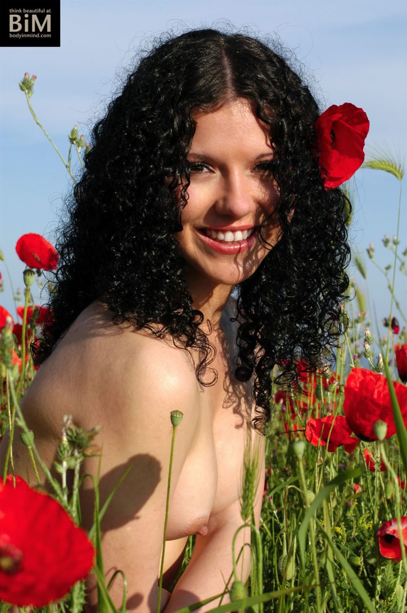 Kamilla, knap en donker haar, is een blote vrouw tussen de bloemen