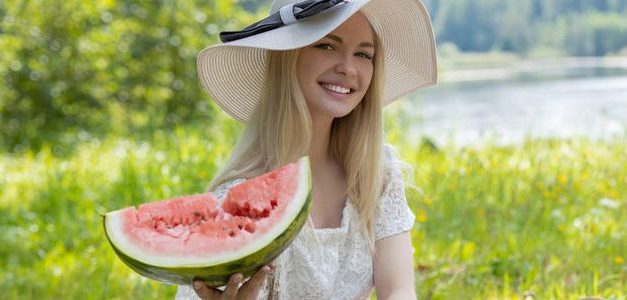 Blonde tiener eet graag buiten een watermeloen op, als ze naakt is